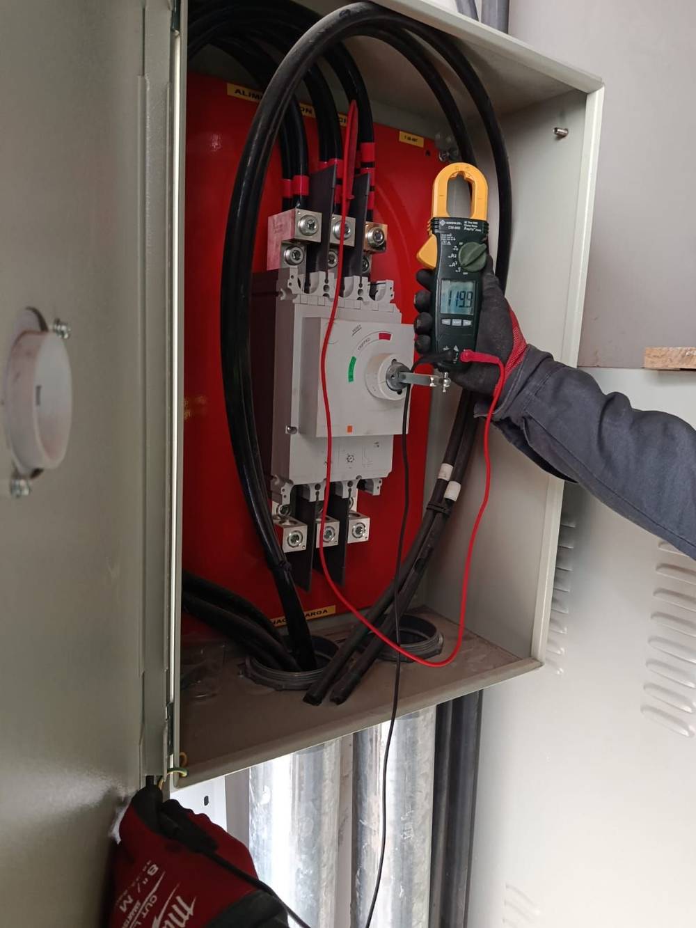 Técnico midiendo con pinza amperimétrica en tablero